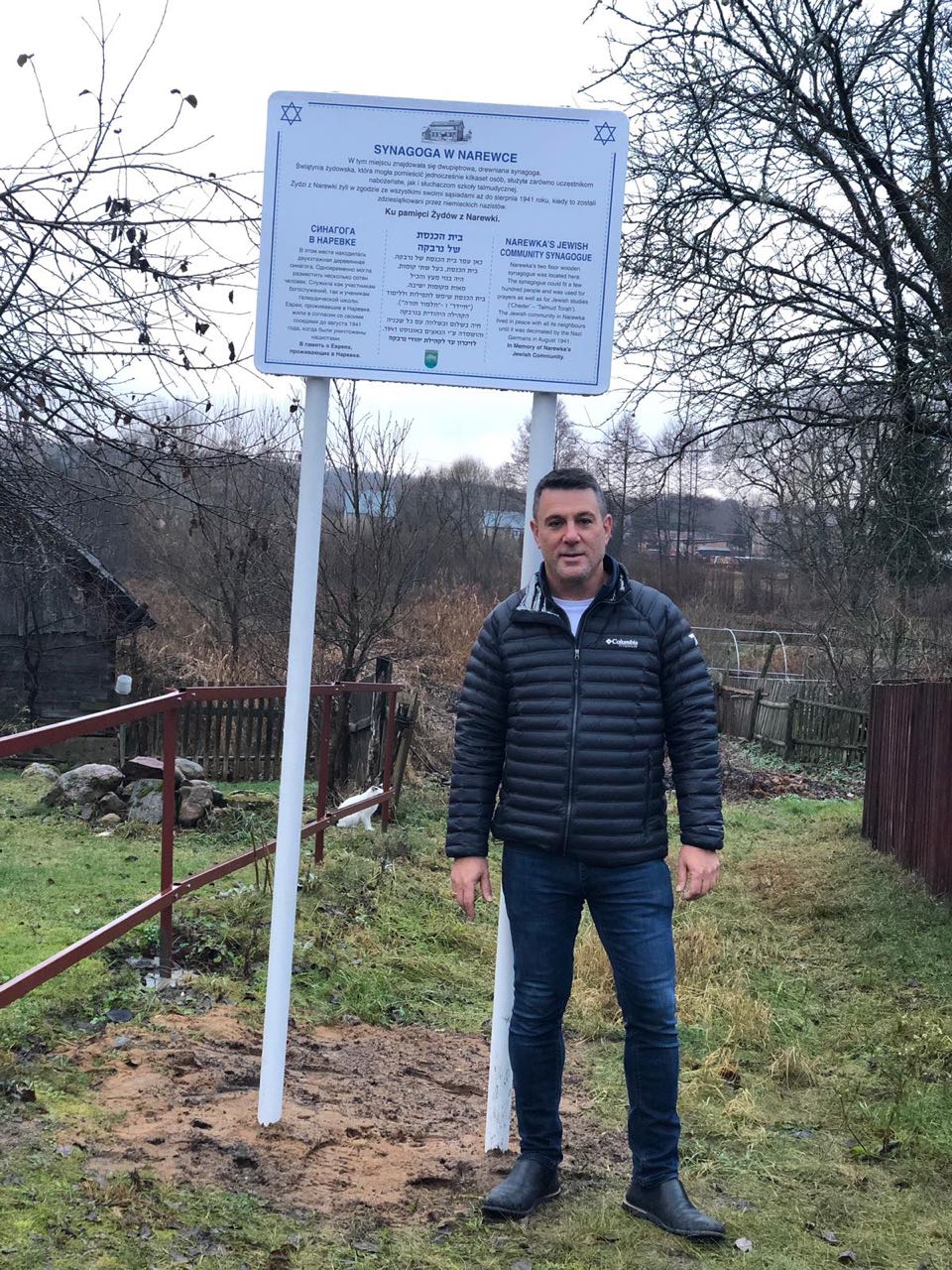 Zvika
                                Birenbaum at sign at synagogue site in
                                Narewka