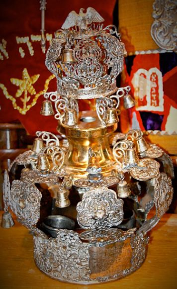 The Stavisht Torah crown's plaque reads, <q>As a remembrance ladies auxiliary _ Sarah ? from Agudas Achim, the people of Stavisht. Charna, daughter of Yisrael Hoffman, President. David, son of Mr. Aharaon Walles, secretary.</q> <em>Note: Agudat Achim Anshei Stavishche in the Bronx, NY was the spiritual home to Stavisht Rabbi Yitzhak Avraham Gaisinsky after he settled in America. Rabbi Gaisinsky brought the crown with him from Stavisht. Read more about the crown and its journey to America on the Stories page. </em>